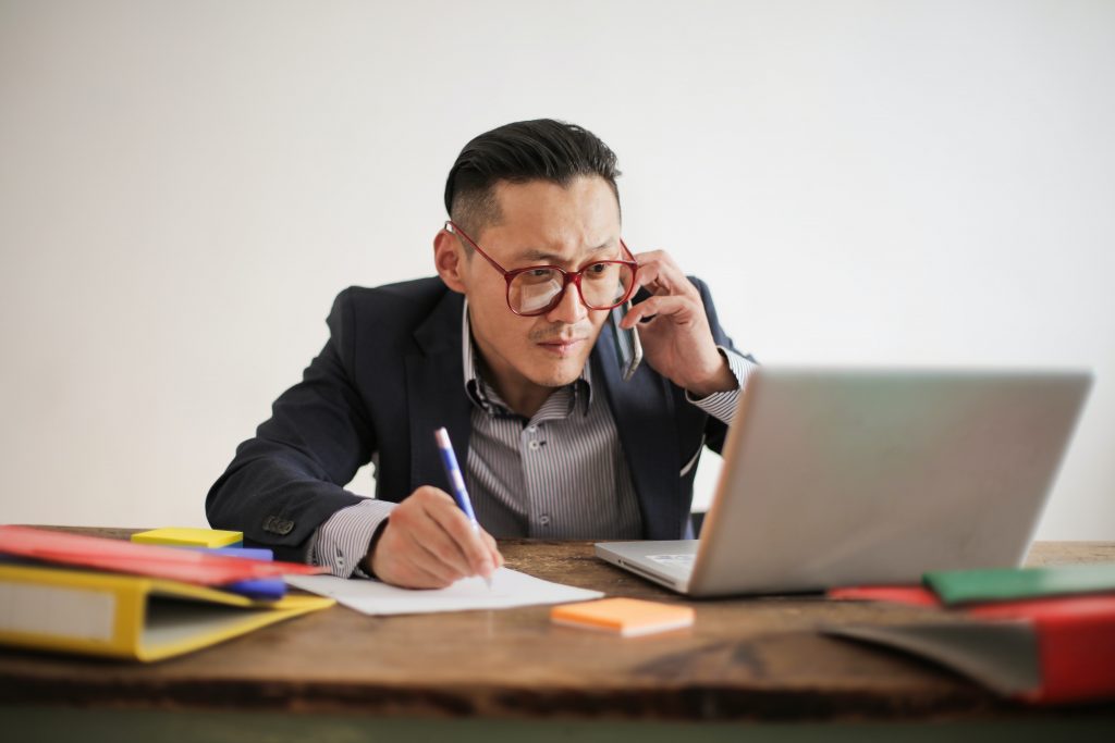 a man looking at a computer and writing on a piece of paper