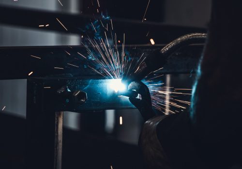 Welding on a hook to a trailer with sparks in a garage
