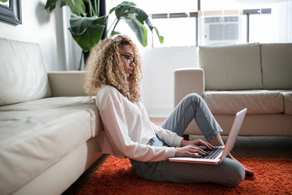 a young woman sitting on the floor and using her laptop