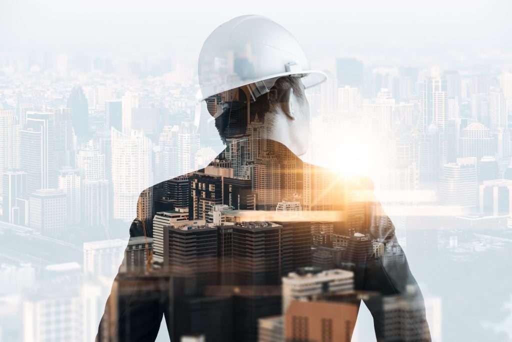 The double exposure image of the engineer standing back during sunrise overlay with cityscape image