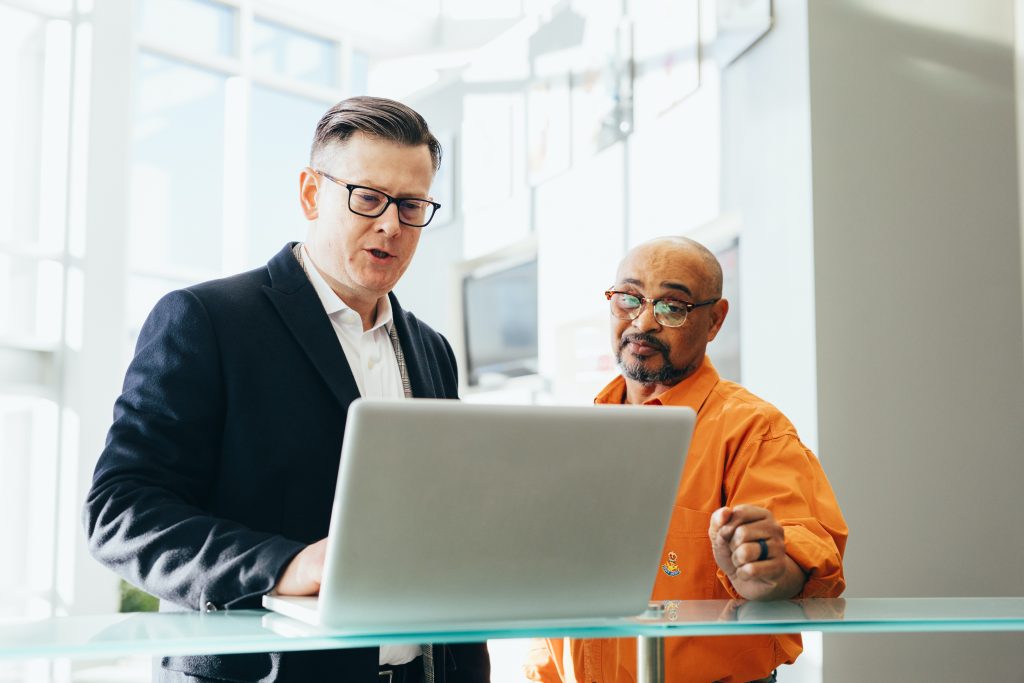 Two men talking with each other on a laptop